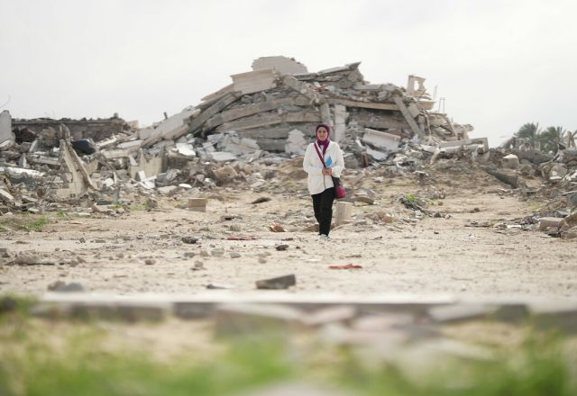 Fidaa Shurrab, Director of Projects at Atfaluna for Deaf Society in Rafah stands in front of a destroyed building in Gaza strip while going to work.