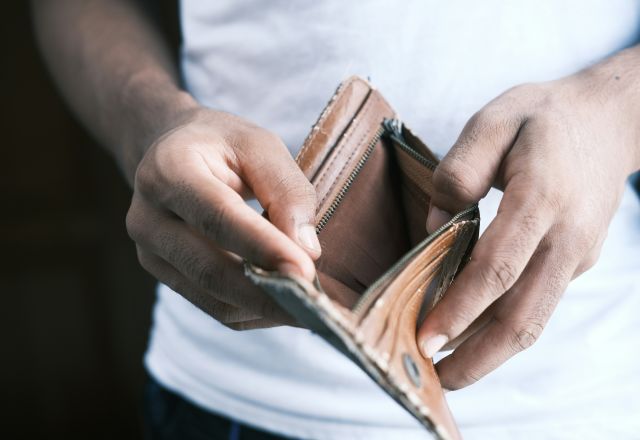 Person in a white t-shirt holding open an empty brown leather wallet.