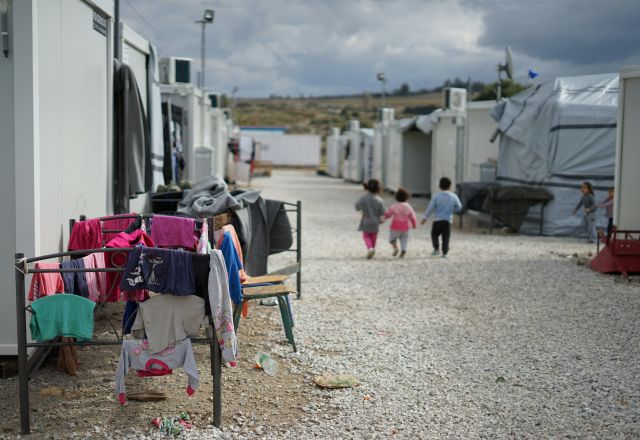 3 children back facing, walking about at an asylum seeker camp