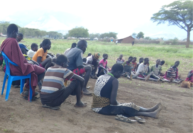 Group of people sitting in semi circle on the floor during a Farmer field schools lesson