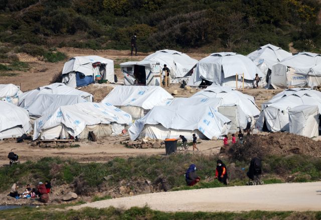 Asylum seekers stand next to tents near the sea at the Mavrovouni camp on Lesbos