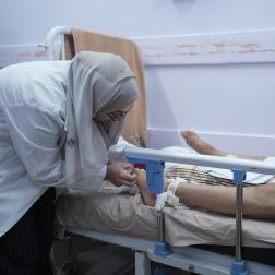 Image of a doctor caring for a patient in an hospital bed.