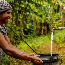 Lavin of Nogorunte community in Papua New Guinea (PNG), shows off the new tap outside her home built by Oxfam's Kōtui Programme