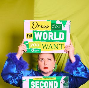 Siobhan McSweeney holding Oxfam's signs "Dress for the world you want" and "Second hand September"