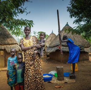 Ngakutoth Biel standing in front of their village with her children